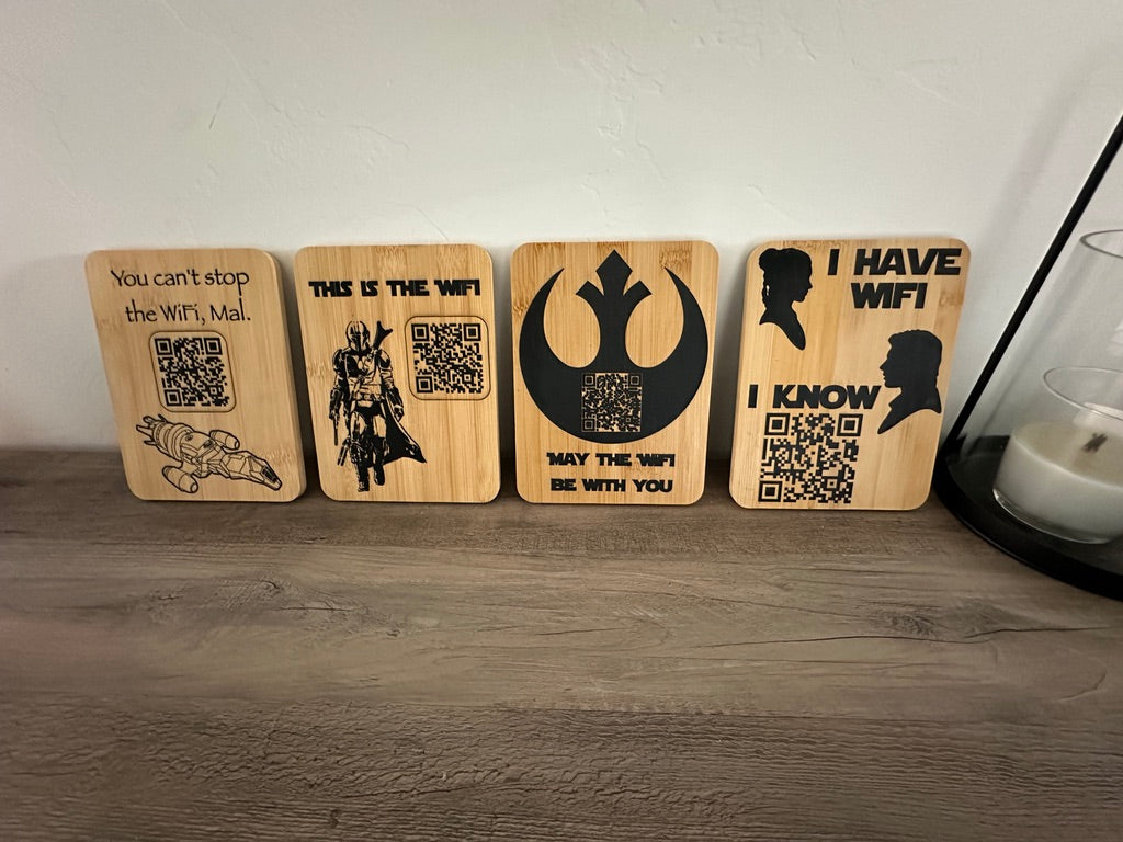 Four rectangular wooden coasters with black Star Wars-themed laser engravings, displayed on a gray wooden tabletop against a white wall.