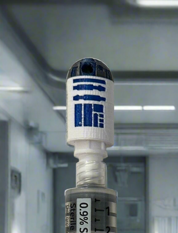 Blue and white dome droid flush cap holder on top of a 10 mL saline flush syringe