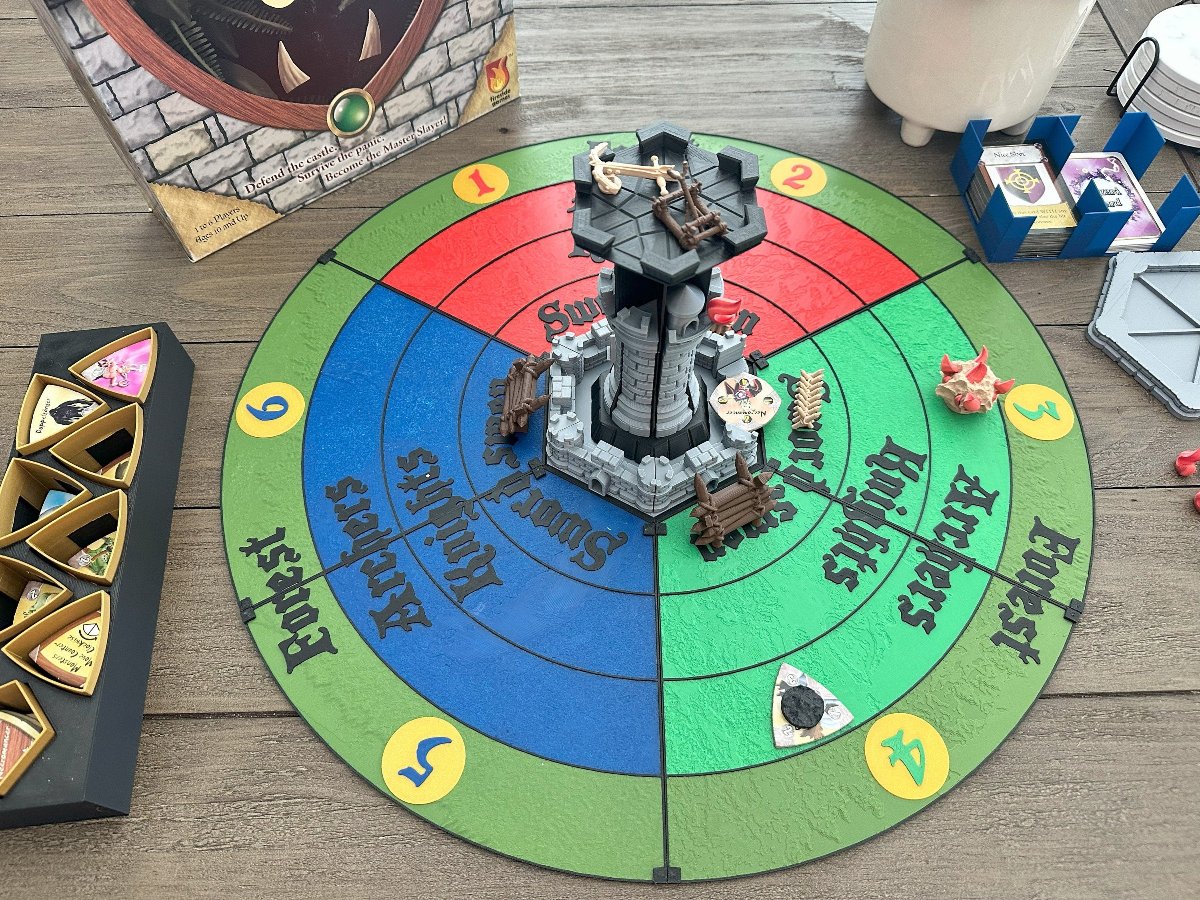 Castle Panic pieces set up on the round replacement game board with cards and monster tokens
