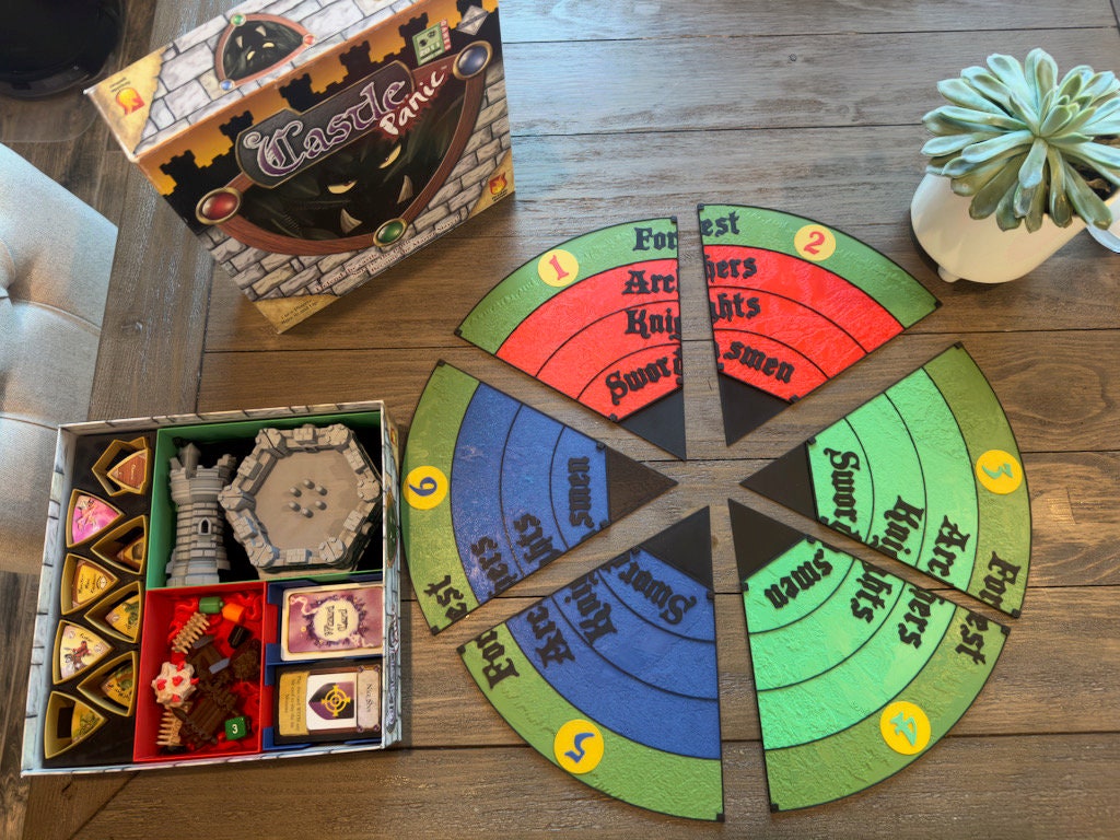 Castle Panic replacement board on a table beside a tray of monster tokens and cards