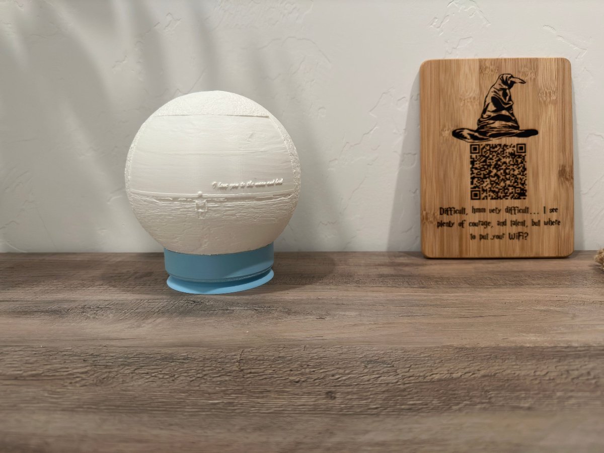 White moon lamp on a blue base on a shelf beside a wooden sign