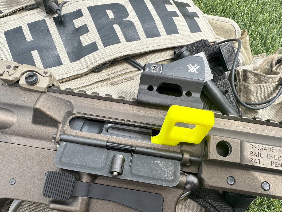Yellow chamber safety flag in an AR-15 rifle resting on a sheriff's vest